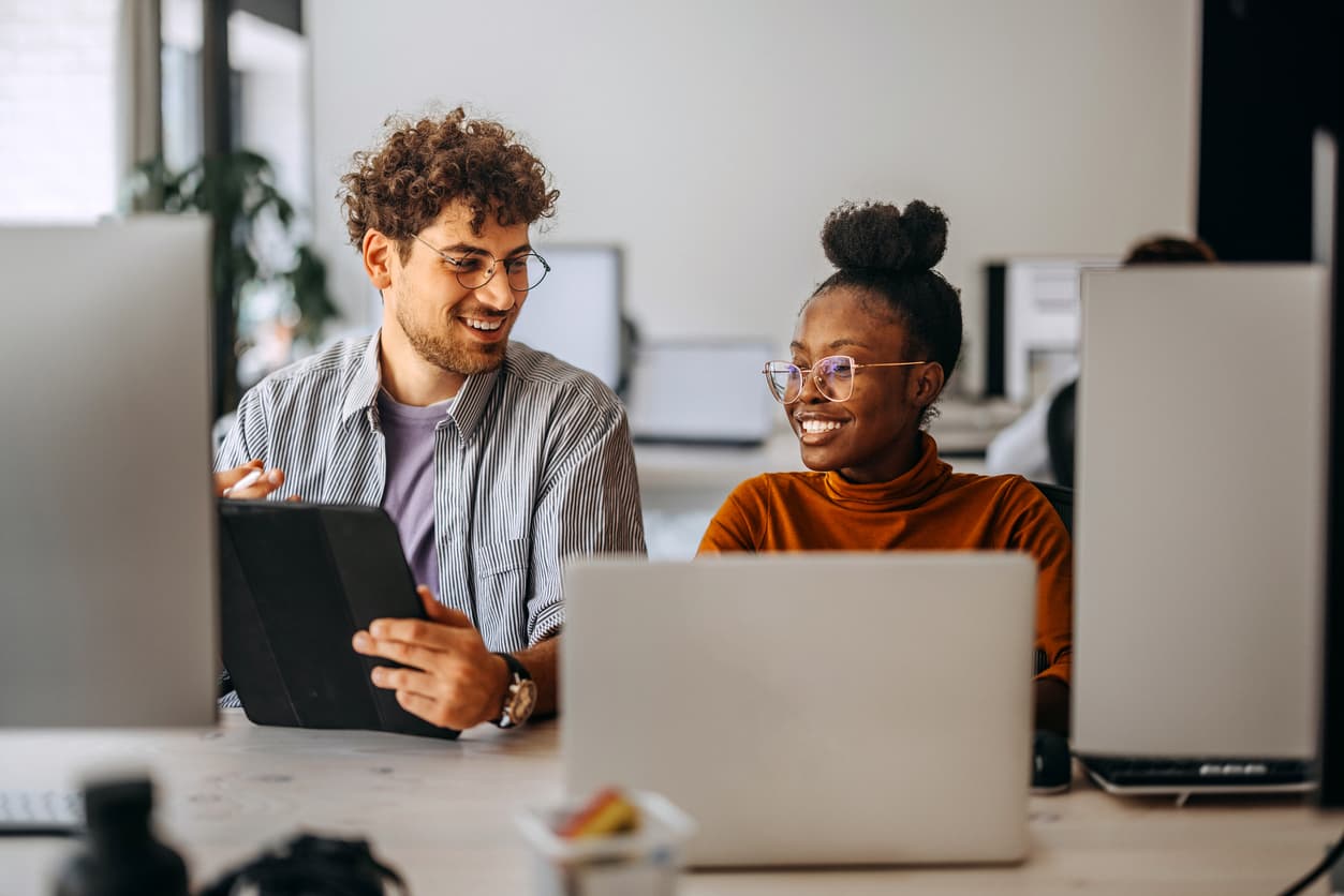 Two colleagues collaborating while using a laptop